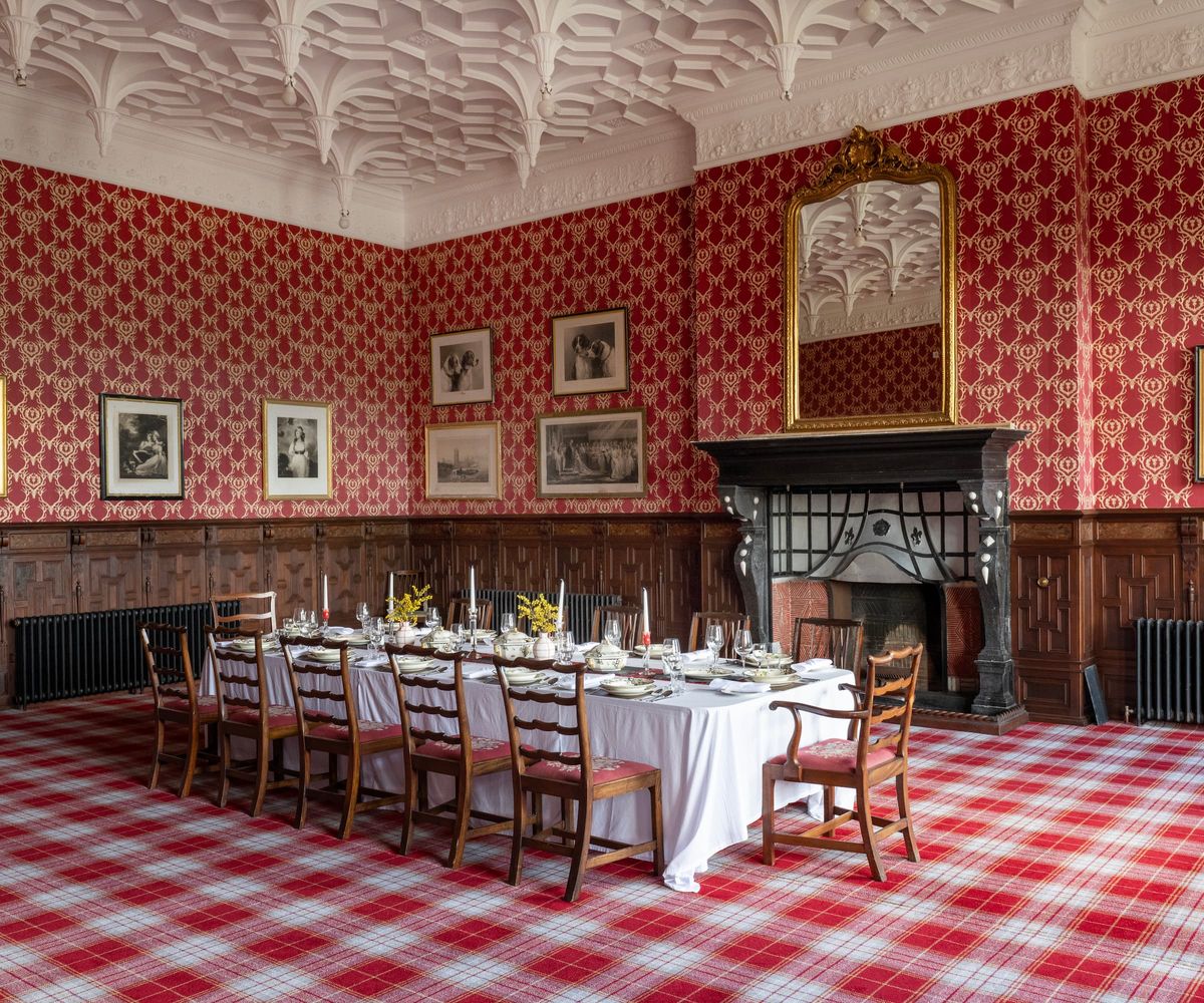 A dining room with a long wooden dining table and fireplace below a large mirror