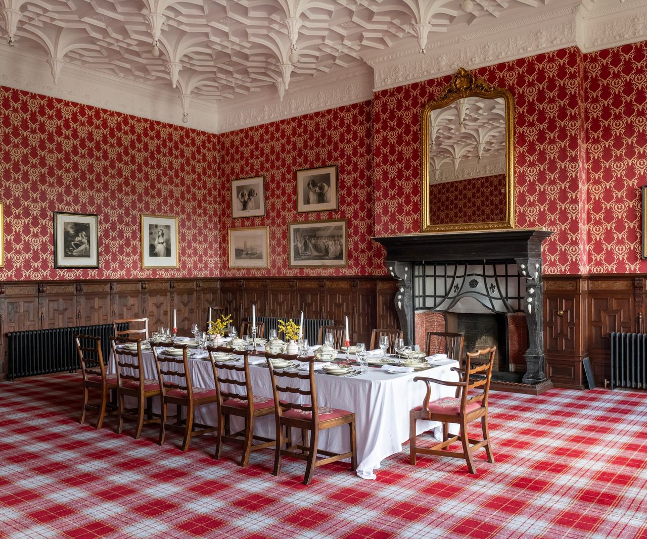 A dining room with a long wooden dining table and fireplace below a large mirror