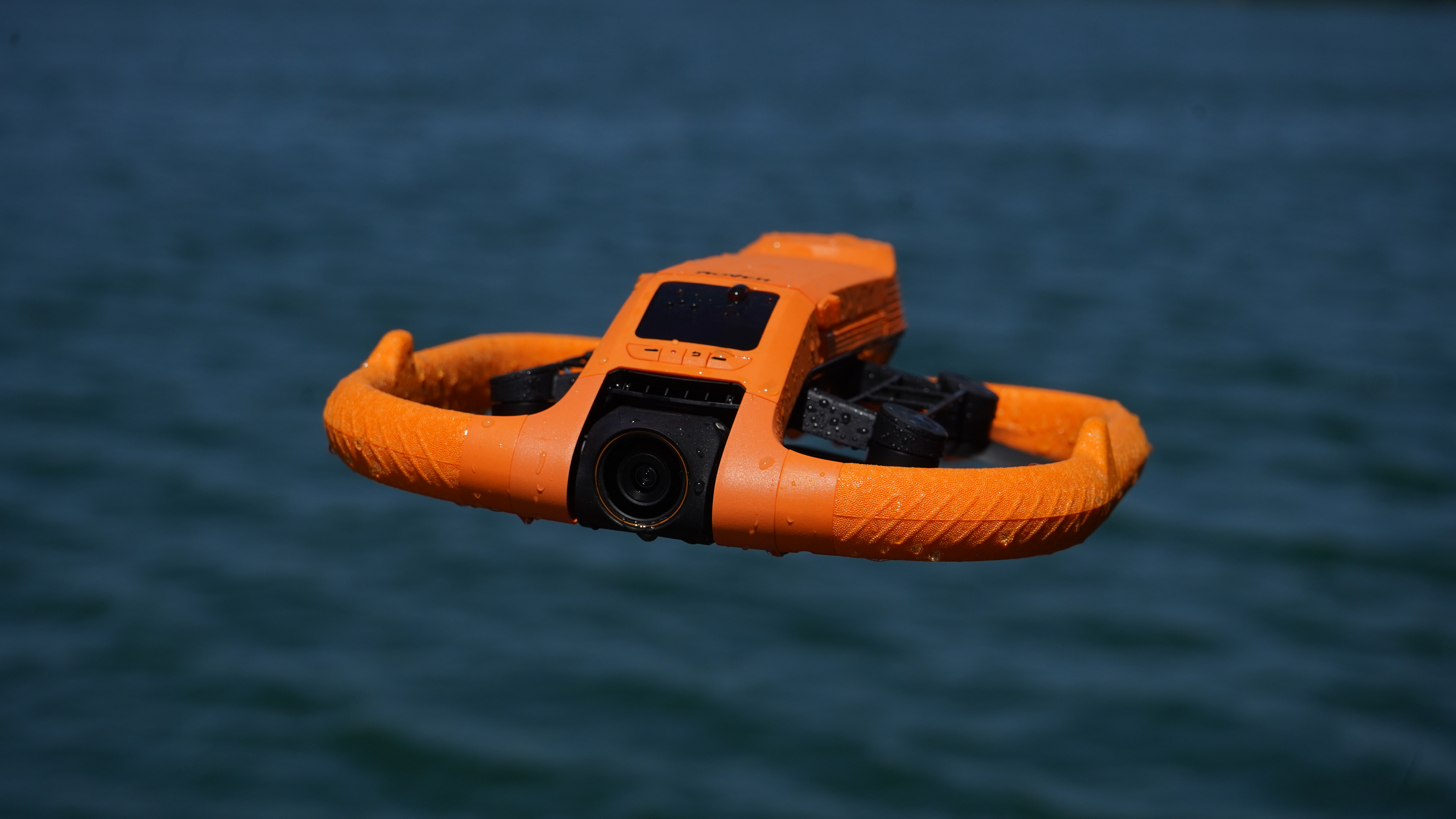 HoverAir Aqua drone flying with water behind and water droplets on it