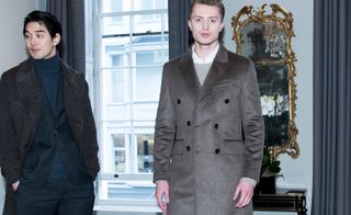 Two male models wearing relaxed turtlenecks under tailored blazers, combined with long tweed coats, often worn closed with a knotted waist tie.