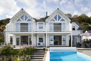 white clad new england style bungalow extension with a pool