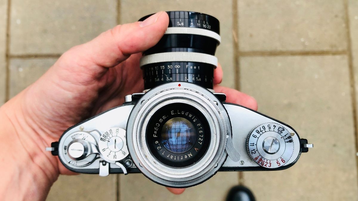 Photographer holding an Exakta V with Magnifying Finder, showing off its magnifying chimney finder