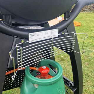 The Weber Q3200 BBQ from the rear with the warming rack and gas canister attached