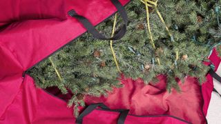 an artificial christmas tree in a red storage bag