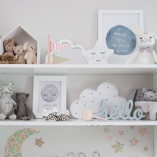 Two white shelves accessorised with prints, cuddly toys and grey and white ornaments