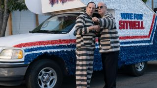 (L to R) Tony Hale as Byron "Buster" Bluth and Jeffrey Tambor as George Bluth Sr. in Arrested Development, wearing black-and-white-striped clothing in front of the stair car.