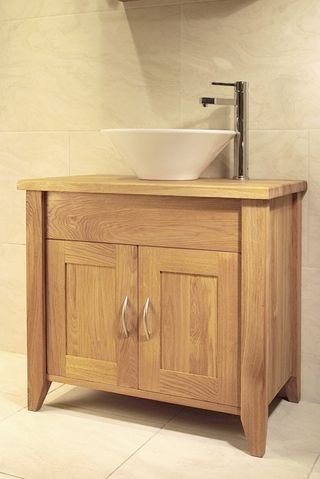 Oak Bathroom Single Washstand in a naturyal oak finish, with a floating sink, shown in a bathroom with large cream coloured tiles