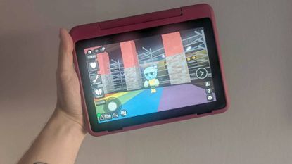 Hand holding Fire HD 8 Kids Pro tablet with Dandy's World gameplay on screen.
