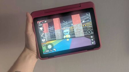 Hand holding Fire HD 8 Kids Pro tablet with Dandy's World gameplay on screen.