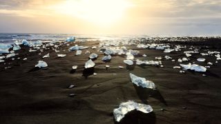 Iceland's Diamond Beach with black sand and chunks of ice that sparkle under the rising sun. 