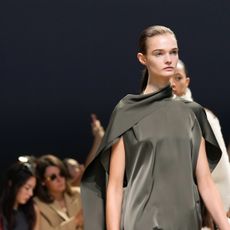 A woman at the COS f/w 24 wearing a green scarf-like blouse.