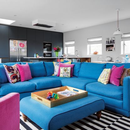 Open plan kitchen living room with blue L-shaped sofa and ottoman