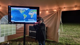 Space.com Editor-in-Chief Tariq Malik with Rocket Lab's launch TV screen tracking an Electron rocket launch.