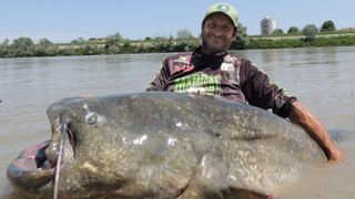 Alessandro Biancardi poses with the catfish on the banks of the River Po.