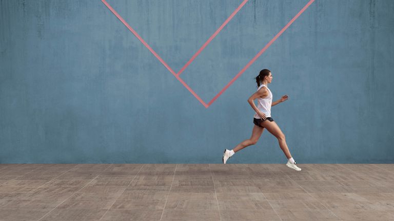 person running in a gymnasium wearing the On Cloud X women's running shoes