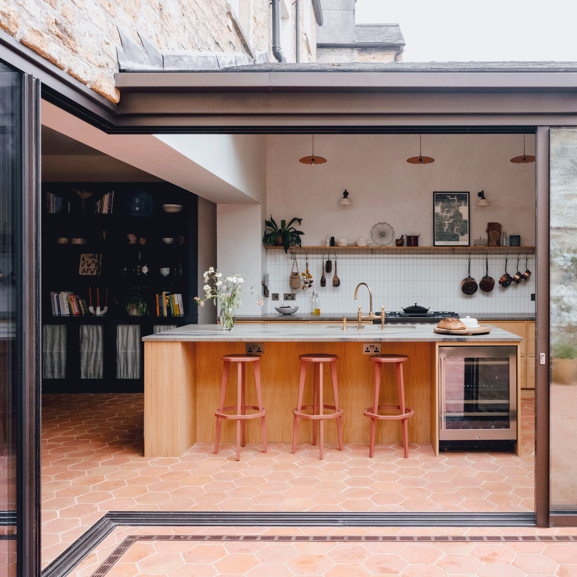 a wooden kitchen with tiled floor and large, sliding patio doors with a kitchen island with breakfast bar