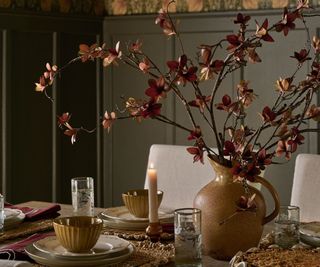 Magnolia dining room set up with crockery on the table and a vase of faux flowers in the middle