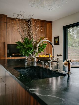 island countertop with sink to match black countertops and backsplash and view of patio doors
