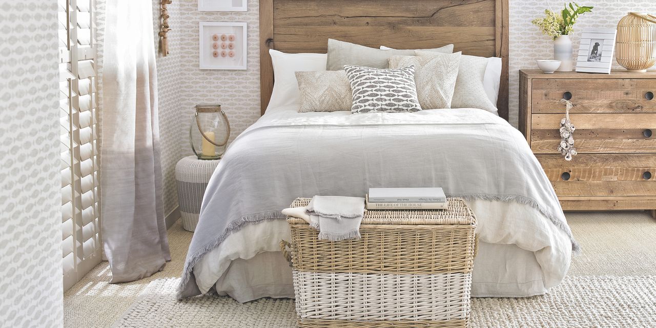 A cream and wooden bedroom with a bed and valance in the centre