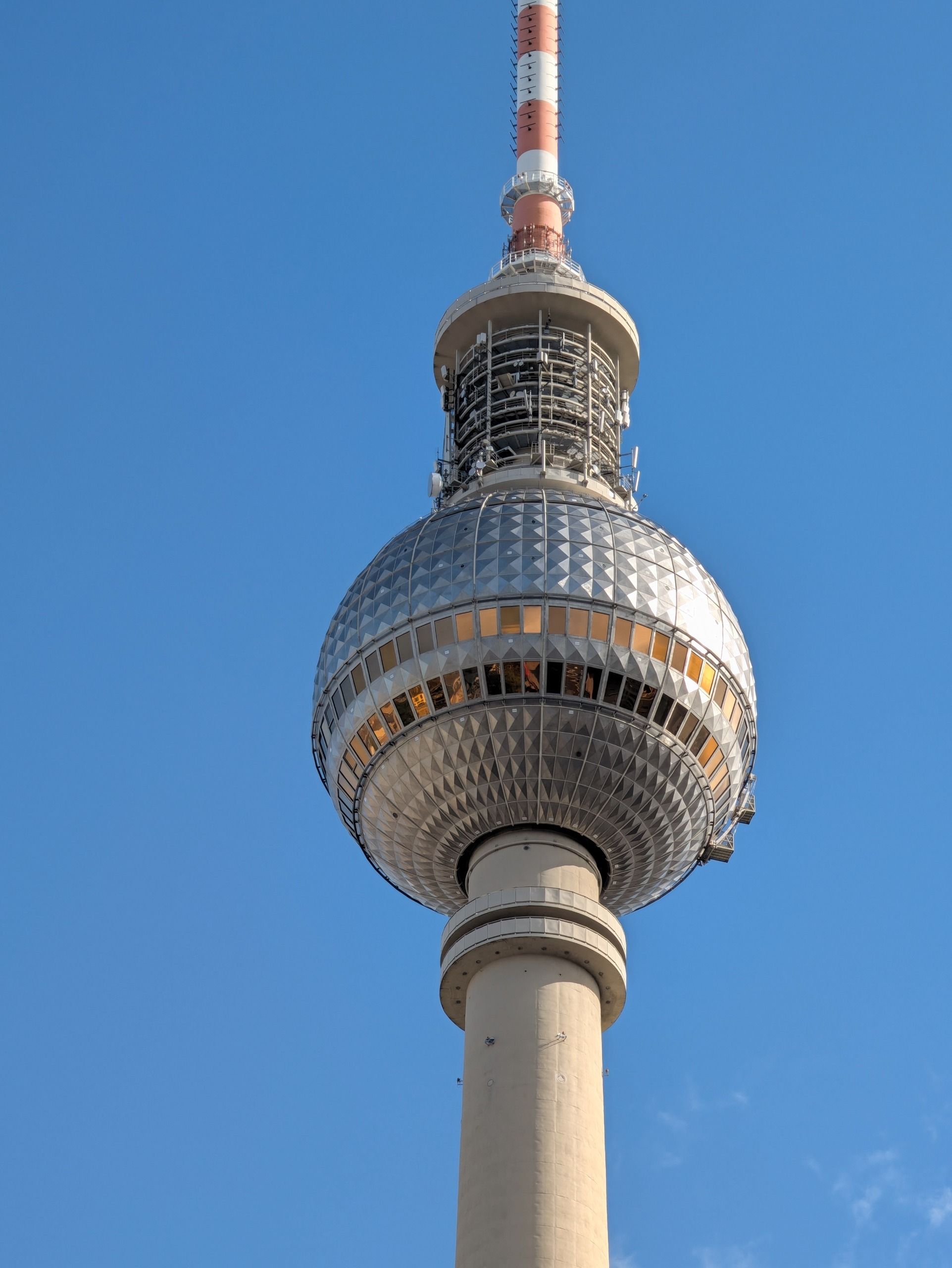Telephoto view of the observation sphere and antenna of Berlin&rsquo;s TV Tower against a clear blue sky.