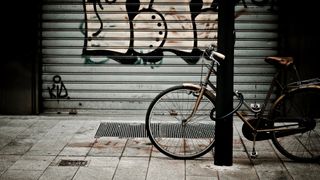 Bicycle parked on street in front of tagged steel rolling shutter.