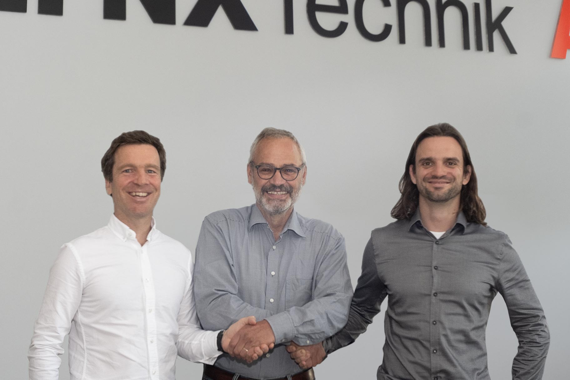 The new Lynx Technik management team, smiling and shaking hands.