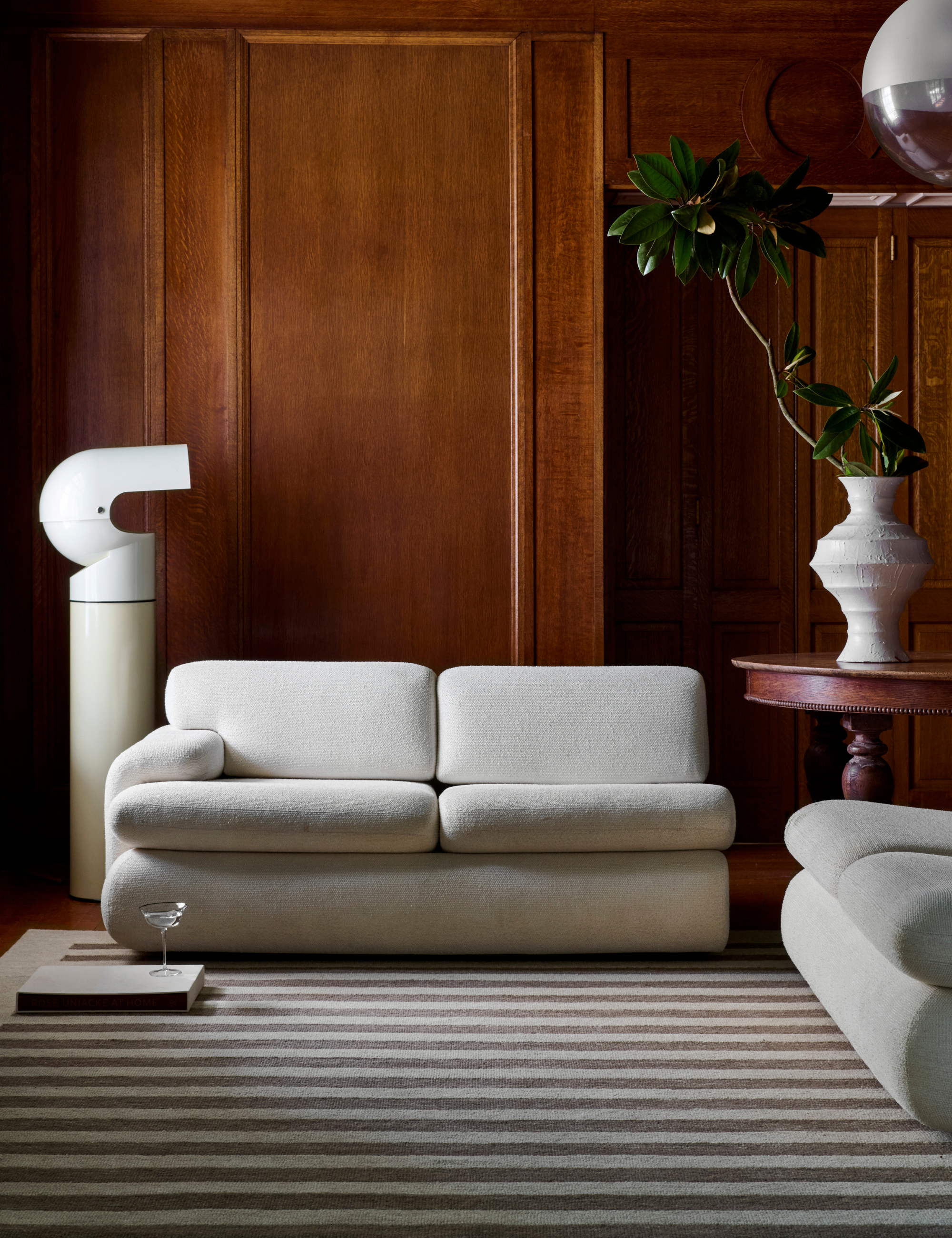 Striped rug featured in a wood-paneled living room featuring modern cream furniture