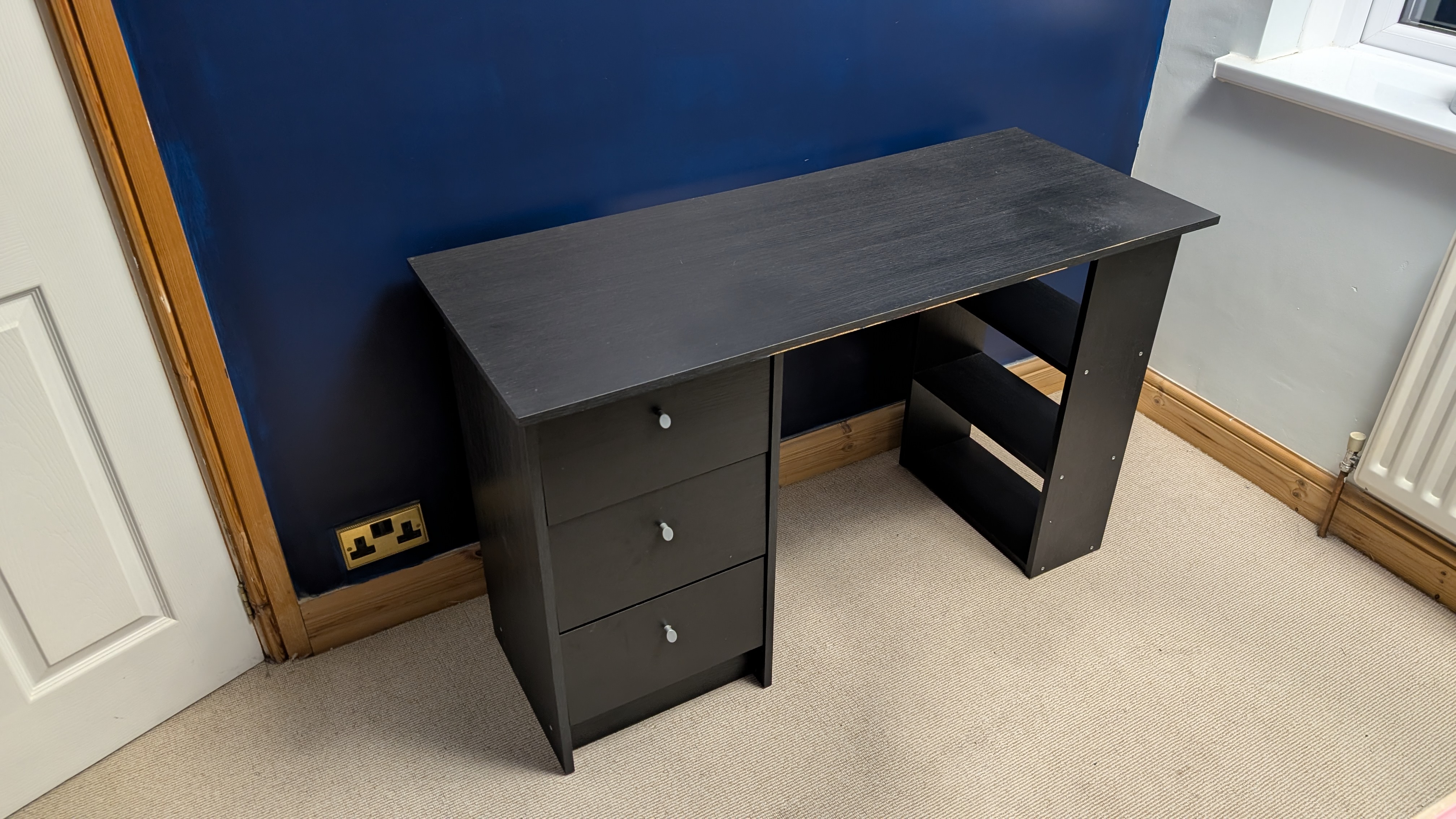 An old black wooden desk with nothing on it and visible signs of wear and tear.