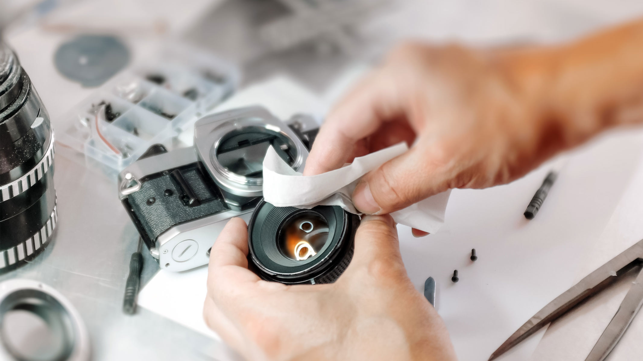 Uma pessoa usando um pano para limpar a lente de uma câmera.