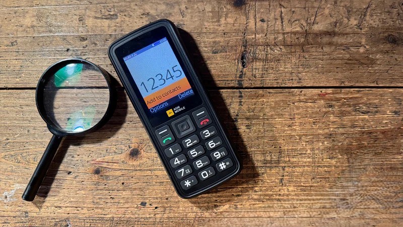 AGM M9 dumbphone and a magnifying glass on a wooden table
