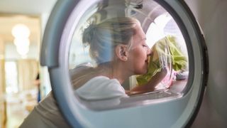 A woman smelling the clothes in a clothes dryer
