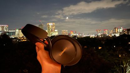 Technics EAH-A1000 in black, in a Tokyo hotel room with the skyline visible 
