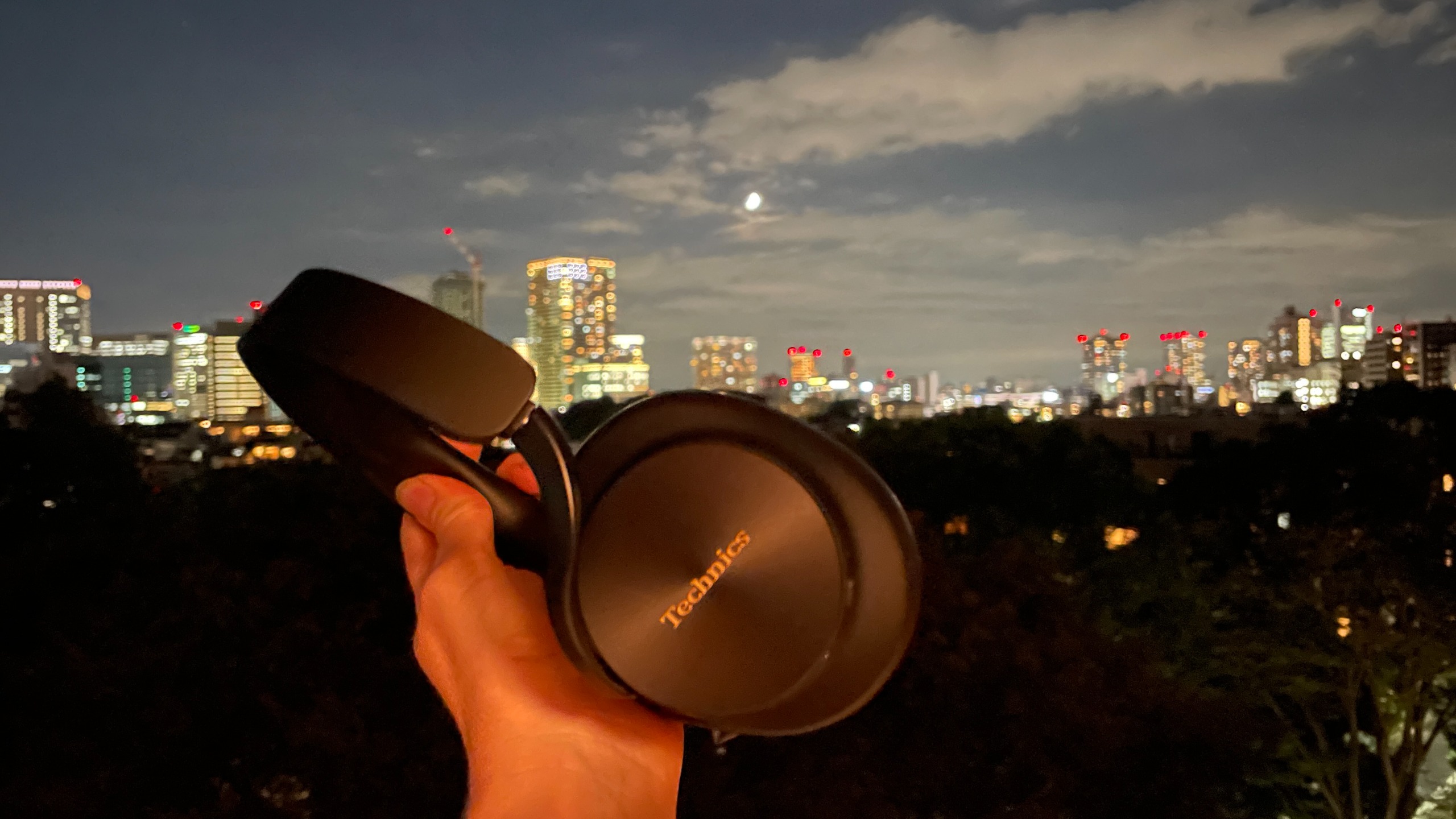 Technics EAH-A1000 in black, in a Tokyo hotel room with the skyline visible 