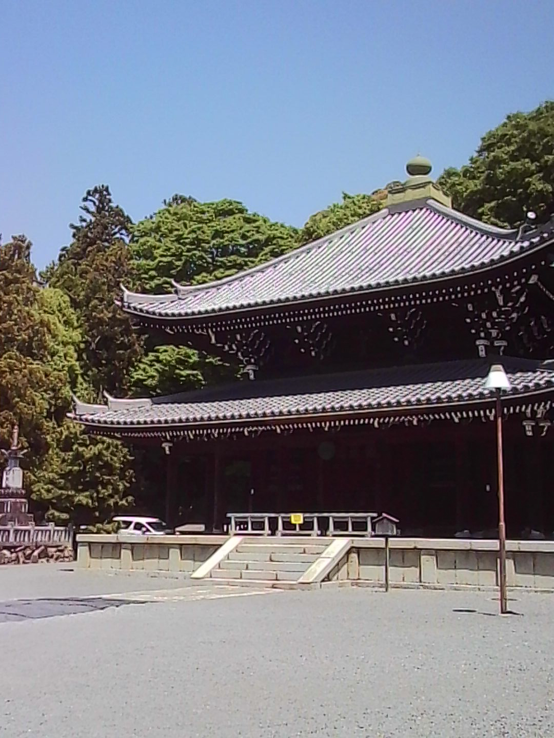 Traditional Japanese temple building with a curved tiled roof under a clear blue sky.
