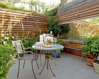 Enclosed patio with mirror and slatted fence