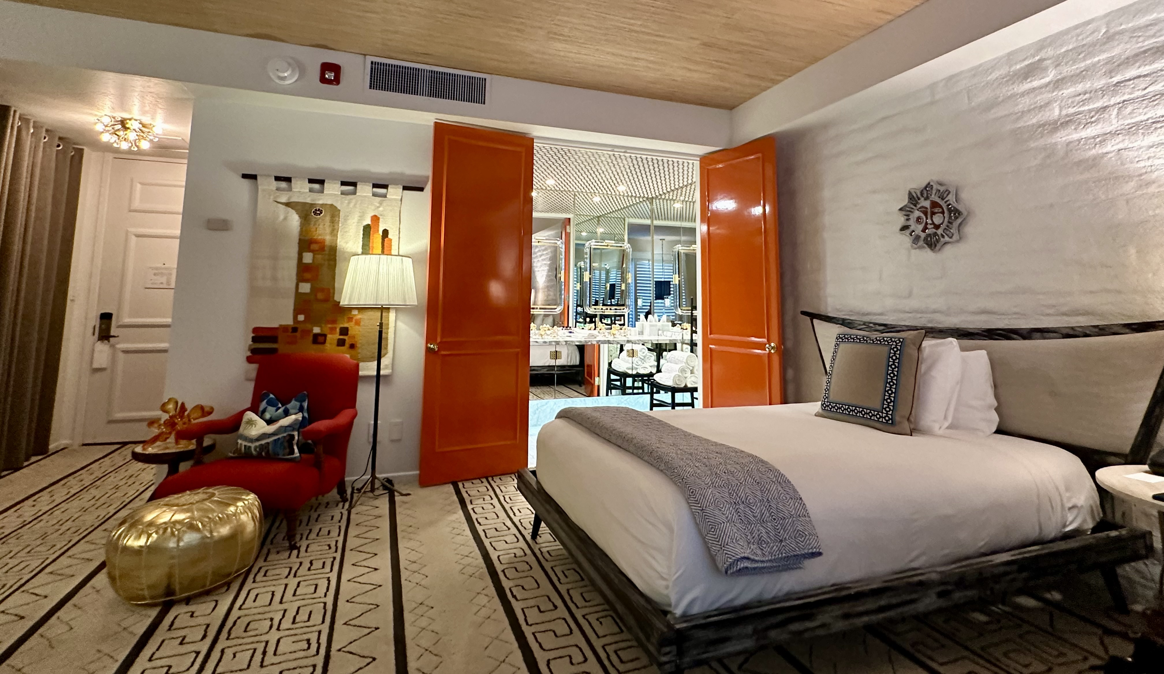 A room at Parker Palm Springs with orange lacquered doors open leading to the bathroom