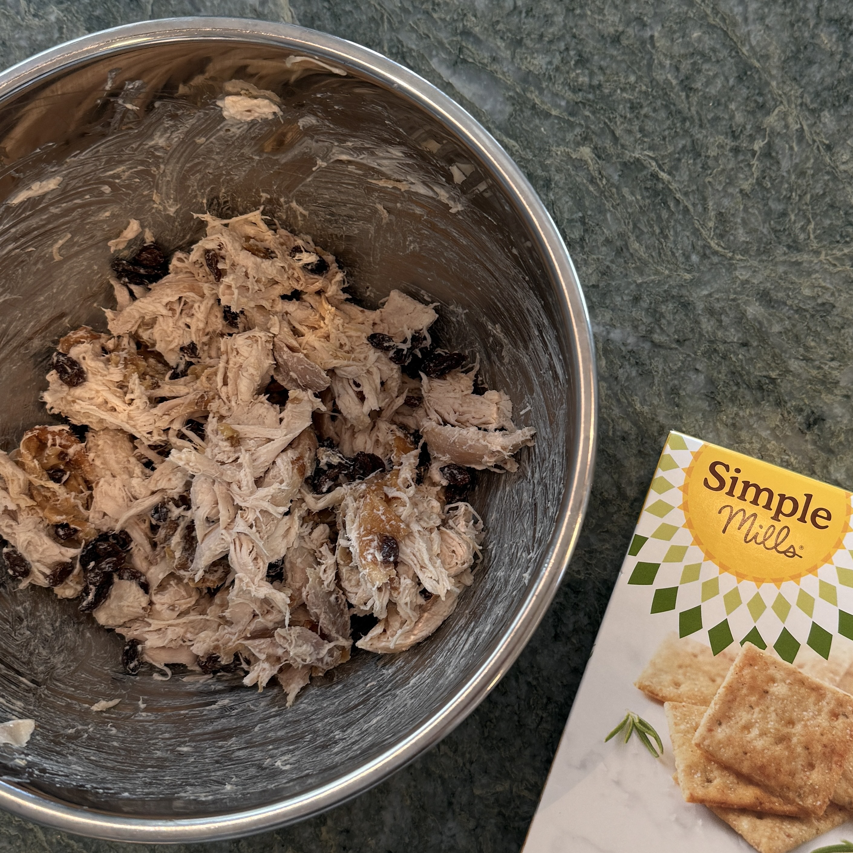 Bowl of chicken and raisins mixed with Greek yoghurt next to a box of Simple Mills crackers