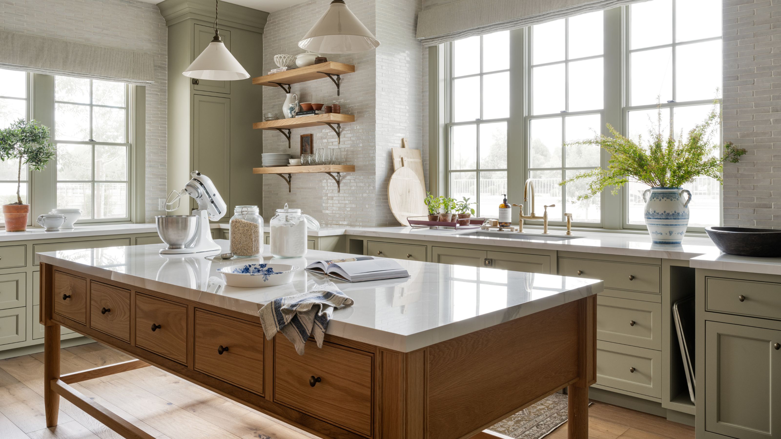 a large butler's pantry painted in a pale green with a large wooden island in the center and a vintage runner rug