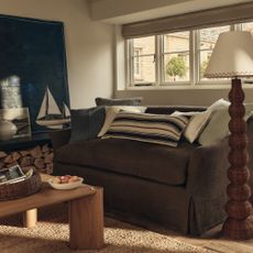 A costal-style living room with a brown linen loose cover sofa and an M&S wicker floor lamp next to it