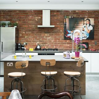 kitchen and dinning room with red brick wall white countertop and chairs