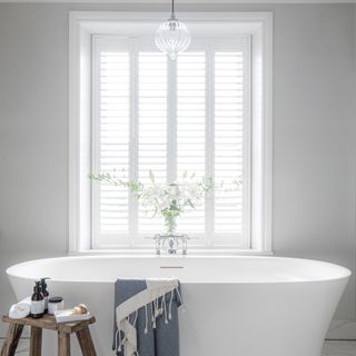 White bathroom with modern bath and shutters