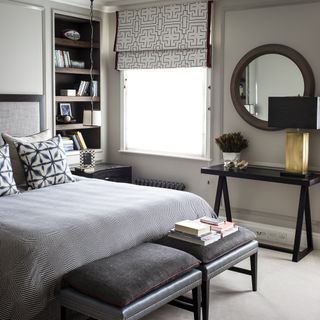 Neutral bedroom with patterned blinds, leather bench and mirror on wall