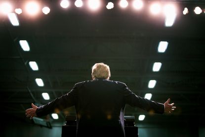 President Trump stands with arms outstretched at a rally