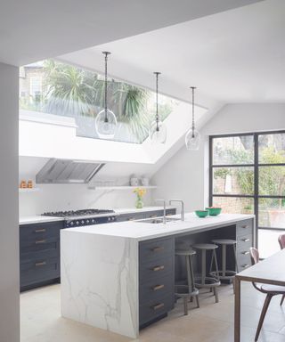 A kitchen with high skylights and floor-to-ceiling windows