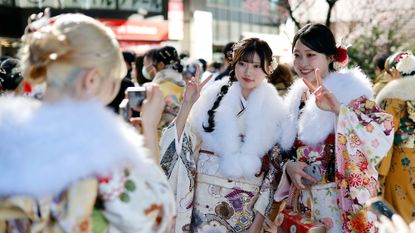 Young women dressed in kimonos take pictures while attending a Coming of Age Day ceremony in Yokohama, Japan