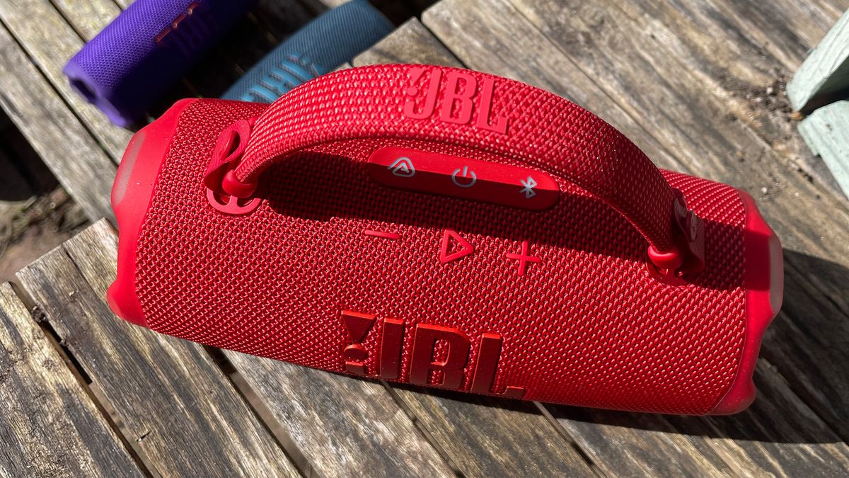 A top-down view of a red JBL Charge 6 wireless speaker on a wooden surface.