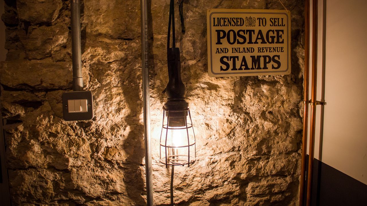 exposed stone walls in a cottage with lamp and electrical trunking