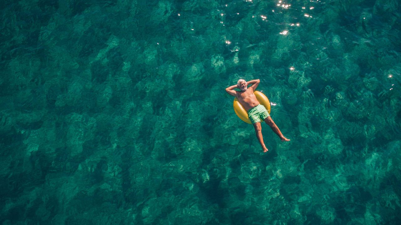 A retiree happily floats in an inner tube.