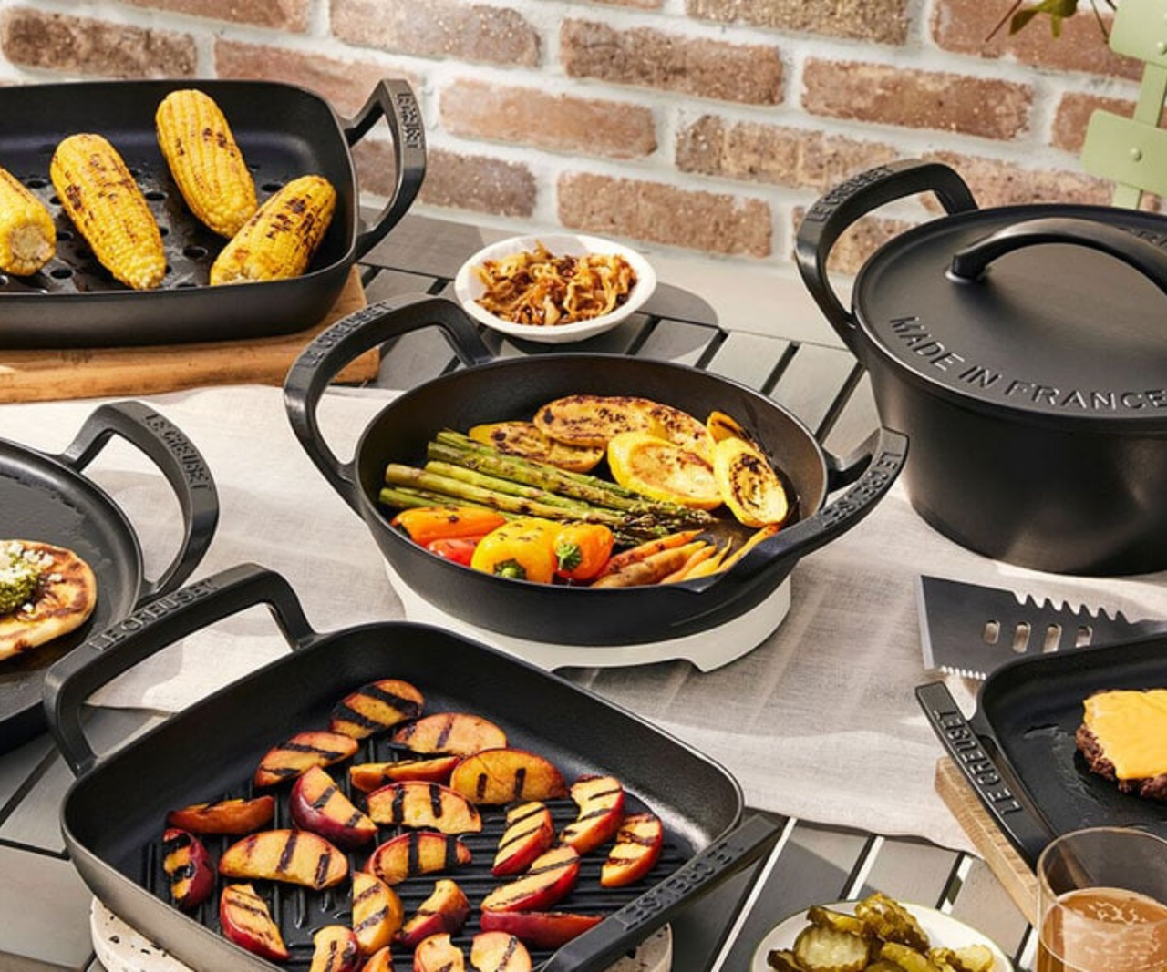 Le Creuset Alpine Outdoor collection arranged on an outdoor table.