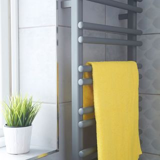 bathroom with grey tiles towel rail and yellow towel